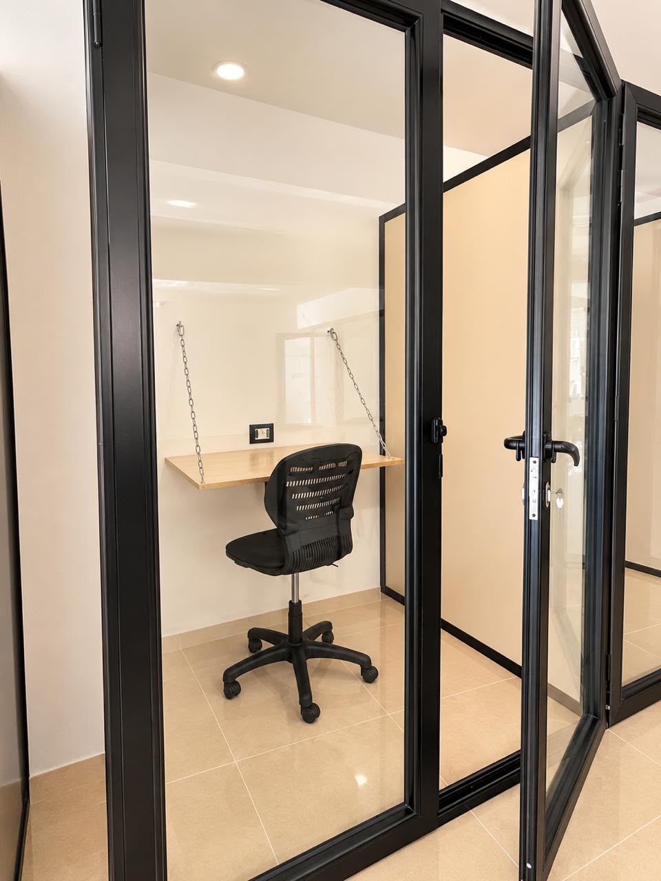 Private glass workspace with a wooden desk and an office chair